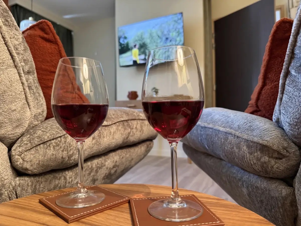 Deux verres de vin rouge sur la table basse face au canapé — Au fil du Cocon, Bulles et Cocon
