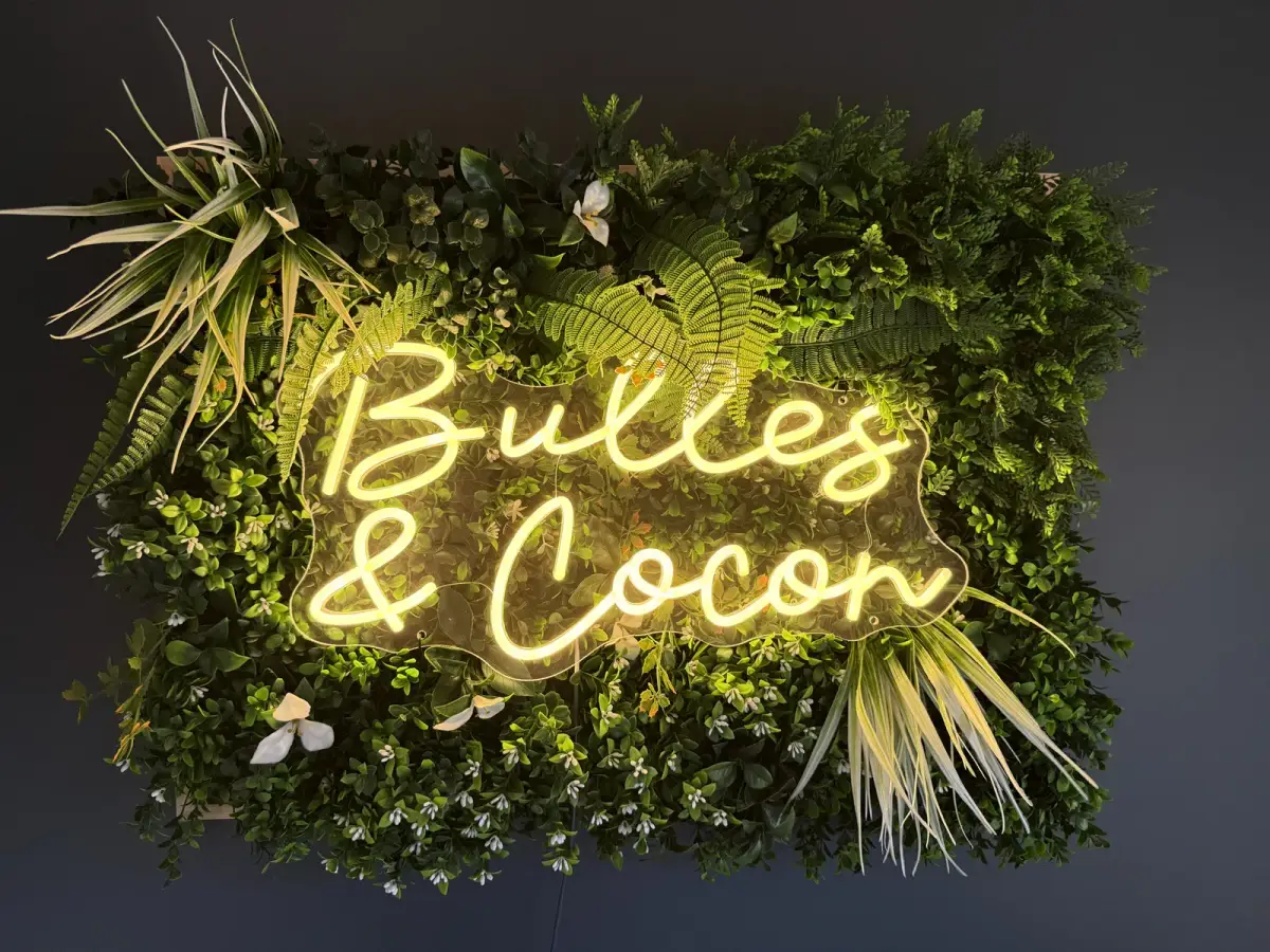 Enseigne néon Bulles et Cocon sur mur de verdure — Bulle Rochoise, Bulles et Cocon