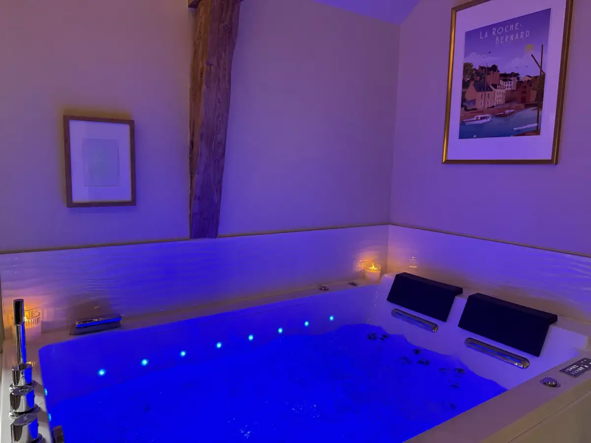 Bain balnéo deux places en lumière bleue tamisée, bougies et affiche de La Roche-Bernard — Bulle Rochoise, Bulles et Cocon