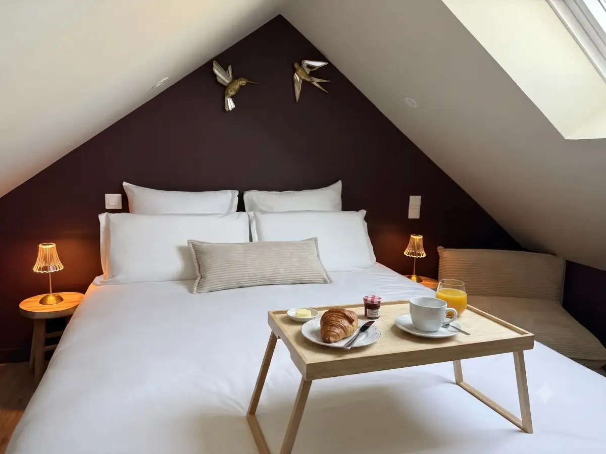 Chambre mansardée, lit double aux draps blancs, mur prune, oiseaux dorés et petit-déjeuner servi au lit — Bulle Rochoise, Bulles et Cocon